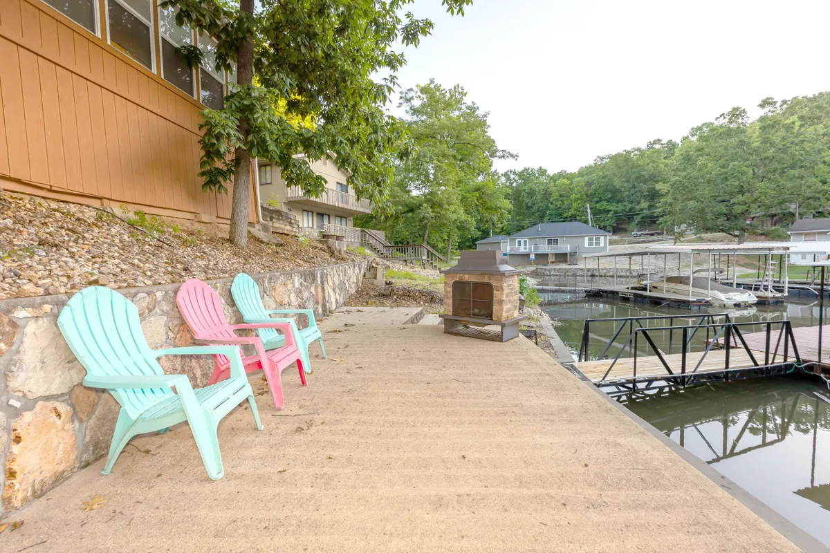A cozy fire pit area on the waterfront, complete with colorful chairs arranged for conversation and a beautiful lakeside view. The setting is ideal for socializing, relaxing by the fire, and taking in sunsets or starlit evenings with friends.