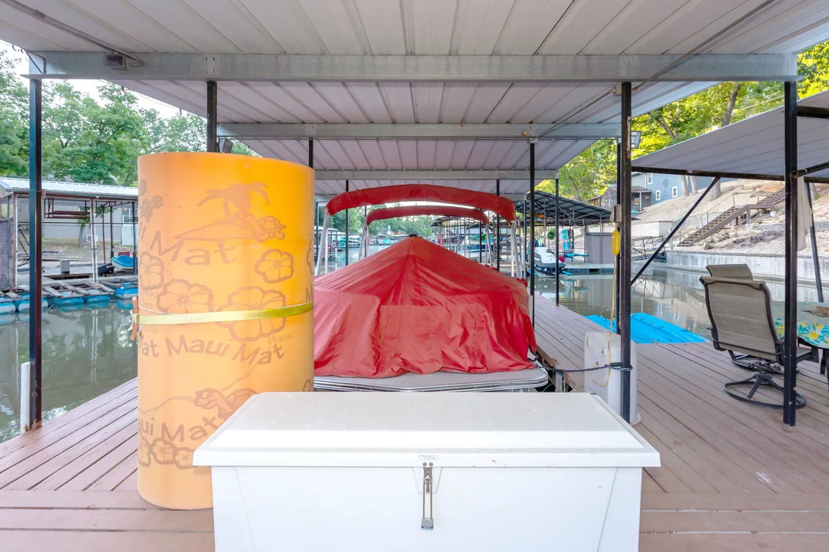 A dockside view featuring a red boat cover, yellow float, and white storage box, framed by water and a relaxed, sunny atmosphere. The scene suggests active water recreation, easy access to gear, and a lifestyle centered around dockside enjoyment.