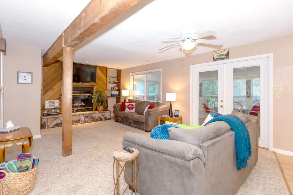 A bright, inviting interior living area featuring a fireplace, comfortable sofas, a coffee table, and—most importantly—large windows that frame expansive outdoor views. The room feels cozy and welcoming, with ample natural light pouring in and an atmosphere ideal for relaxation and family gatherings.