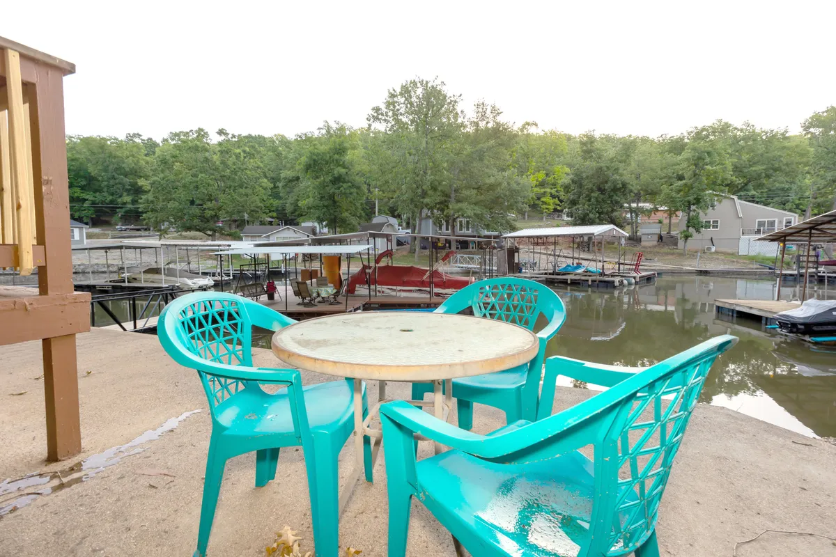 A welcoming outdoor dining area with turquoise chairs and a round table set by the water, offering a clear view of the lake. The setup radiates a sense of tranquil leisure, perfect for morning coffee, evening meals, or stargazing after sunset.