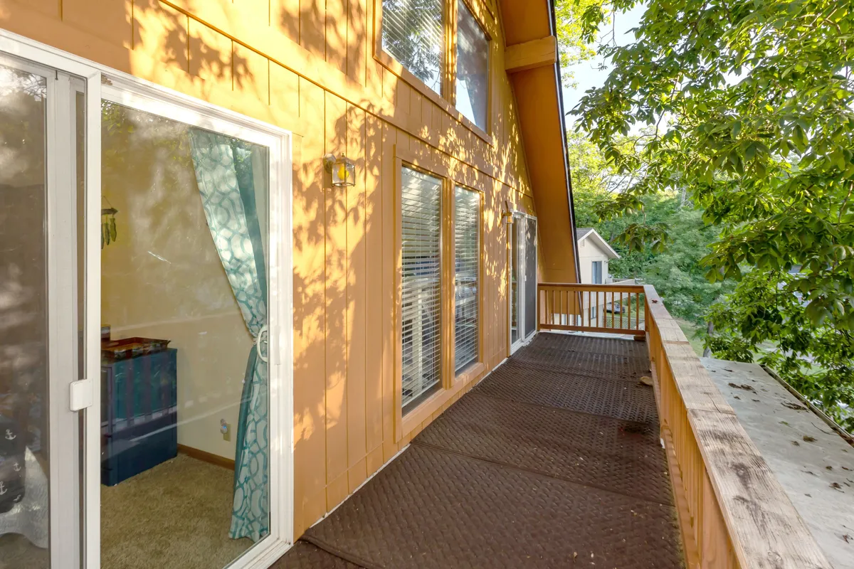 An exterior perspective of the deck, with a rail overlooking the landscape and large windows revealing interior decor. The space invites you to imagine enjoying morning coffee or evening sunsets from the elevated vantage point, with a seamless indoor-outdoor transition.